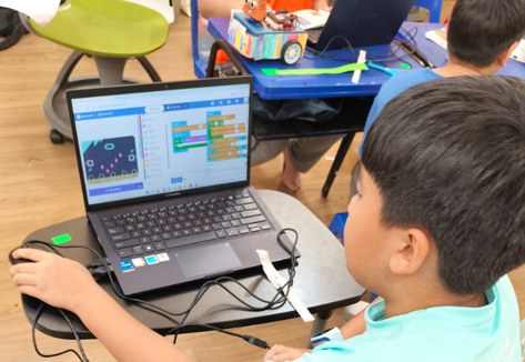 A child programming a project with visual coding blocks