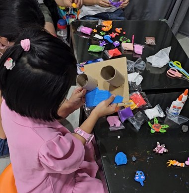 A child shaping colorful clay pieces during a craft workshop